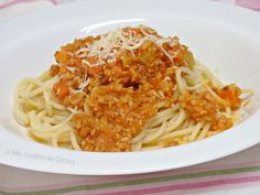 a white plate topped with pasta covered in sauce and cheese on top of it next to a striped table cloth