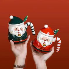 two handmade christmas mugs with santa hats and candy canes in their hands