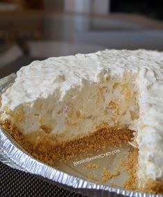 a cake with white frosting on it sitting on top of a pan covered in tin foil