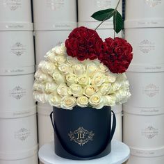 a blue bucket with white and red roses in it sitting on a table next to stacks of books