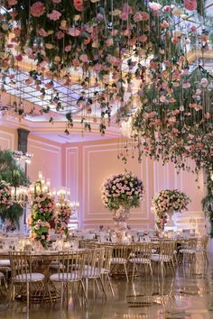 a room filled with lots of tables and chairs covered in pink flowers hanging from the ceiling