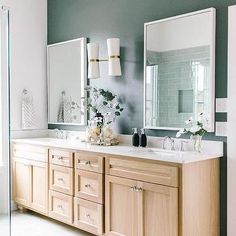 a bathroom with two sinks, mirrors and lights on the wall above them is decorated in shades of green and white