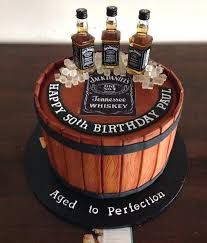 a birthday cake made to look like a barrel with three bottles of whiskey on top