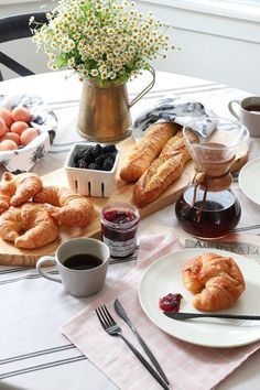 the table is set with croissants, coffee, and other breakfast foods