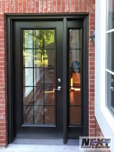 a black double door on a brick building with glass panels and sidelights, in front of a patio area