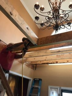 a man working on a light fixture in a room that is being remodeled with wood