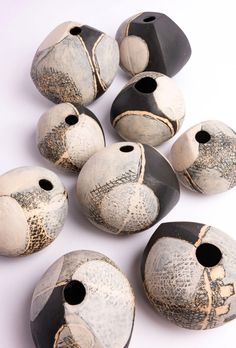 several black and white vases with holes in them on a white surface, including one that has been made from clay