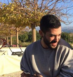 a man with a goatee on his head sitting in front of a table outside