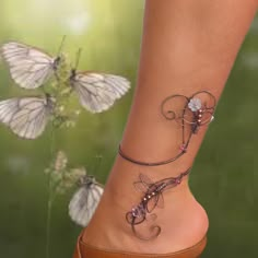 a woman's foot with two butterflies on it and one butterfly flying in the air