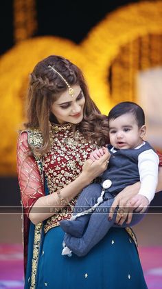 a woman holding a small child in her arms while wearing a red and blue outfit