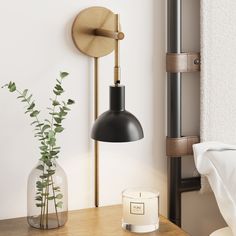 a black and gold wall light next to a vase with a plant in it on a wooden table