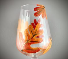 a wine glass with leaves painted on it