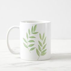 a white coffee mug with green leaves on it