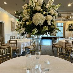 a vase filled with white flowers sitting on top of a table next to two wine glasses