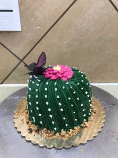 a cake decorated with green icing and pink flowers on top of a metal platter