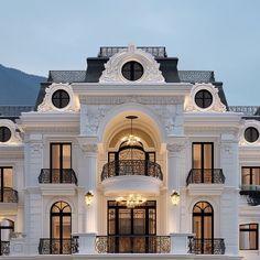 a large white building with lots of windows and balconies on the top floor