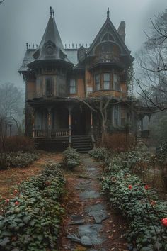 an old victorian style house in the middle of a foggy forest with flowers growing on the ground