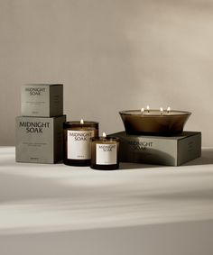 three candles sitting next to each other on top of a white tablecloth covered surface