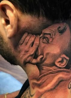 a man with tattoos on his neck covering his face