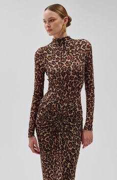 a woman in a leopard print dress with high neck and long sleeves, standing on a white background