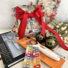 some items are laying out on a bed with a red ribbon around them and an ornament next to it