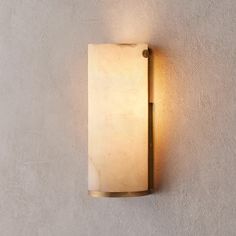 a white wall light mounted on the side of a concrete wall with a small bulb