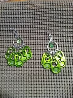 the green earrings are hanging from silver hooks