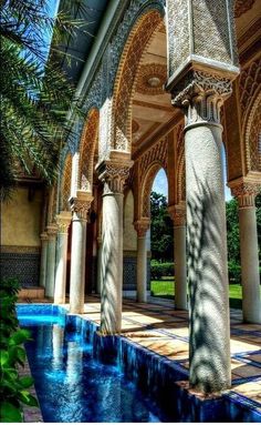 an outdoor swimming pool surrounded by columns and arches