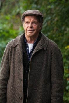 an older man wearing a brown coat and hat