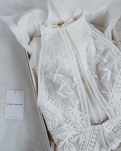 an open box with white lace on it and a tag attached to the inside of it