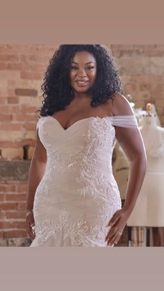 a woman in a wedding dress posing for the camera with her hands on her hips