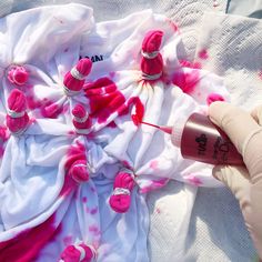 someone is painting the fabric with pink and white paint on it, while wearing gloves