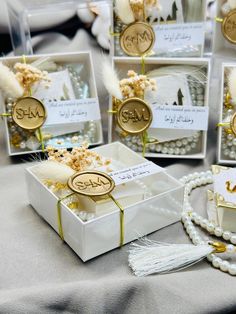 small white boxes filled with pearls and other items on top of a cloth covered table