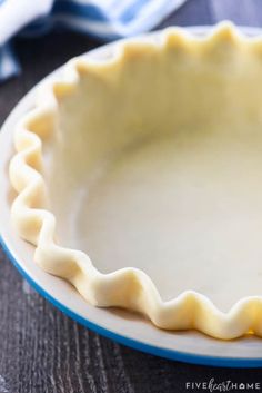 an uncooked pie crust sits on a white plate with blue trim around the edges