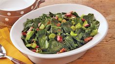 a white bowl filled with green vegetables next to a yellow napkin and silverware on top of a wooden table