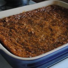 a blue and white casserole dish filled with food on top of a stove