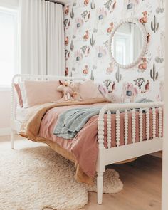 a white bed sitting in a bedroom next to a wallpaper covered with cactus designs