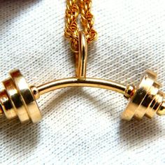 a gold necklace with two dumbs attached to it