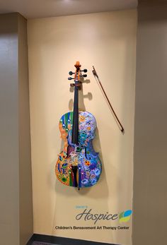 a violin is hanging on the wall next to a sign that says haspice children's environment art therapy center