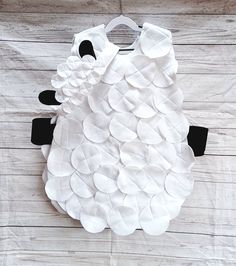 a sheep made out of white paper sitting on top of a wooden floor