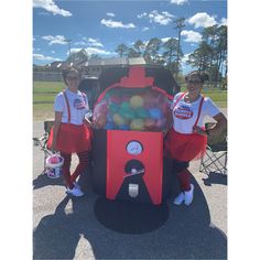 two women in red and white outfits standing next to a trunk filled with candy