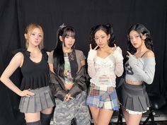 four young women posing for a photo in front of a black background