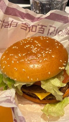 a hamburger with lettuce and cheese in a paper wrapper on a table