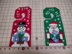 two christmas door hangers with santa and snowman on them, one is green and the other is red