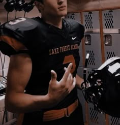 a man in a football uniform standing next to lockers