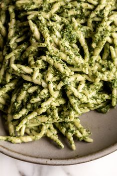 pasta with pesto sauce in a bowl on a marble countertop, ready to be eaten