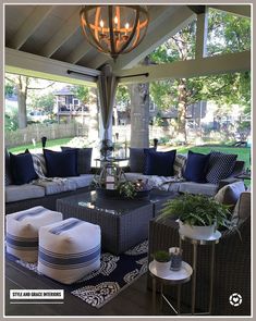 an outdoor living area with couches, tables and pillows on the floor in front of a gazebo