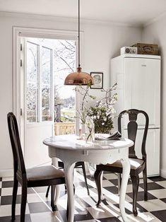 a white table and chairs in a room with black and white checkered flooring