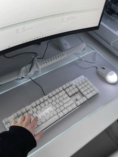 a person typing on a computer keyboard and mouse at a desk with two monitors behind them