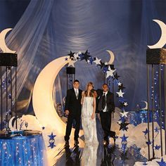 three people standing in front of a backdrop with stars and moon